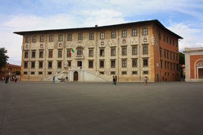 People on street by buildings in town against sky