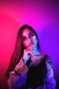 Portrait of young woman against illuminated background