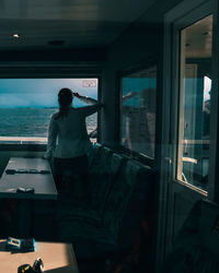 Rear view of woman looking at sea through boat window