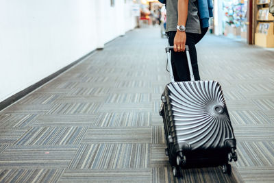 Low section of woman carrying suitcase walking on street