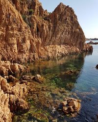 Rock formation on shore against sky