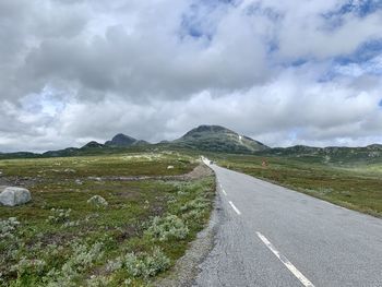 Road leading towards mountain against sky