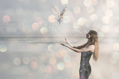 Digital composite image of young woman with owl at beach