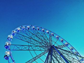 Low angle view of ferris wheel against blue sky