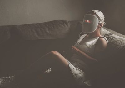 Woman using technological equipment on sofa at home