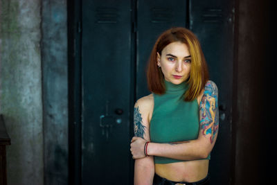 Portrait of young woman standing against door