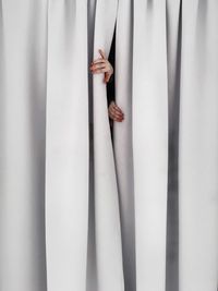 Cropped hands of woman separating curtains