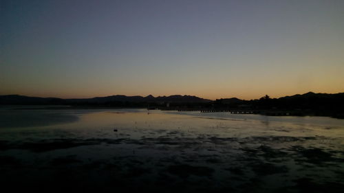 Scenic view of beach against clear sky during sunset