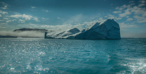 Iceberg against cloudy sky