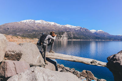 Man photographing lake against sky