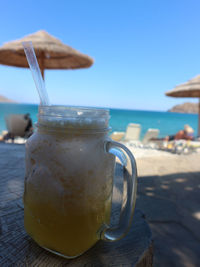 Close-up of drink on table at beach against sky