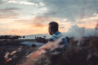 Side view of man on beach against sky during sunset