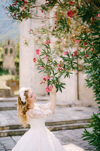 Young woman with flower bouquet against tree