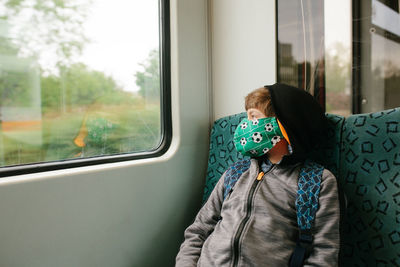 Boy wearing mask while traveling in train