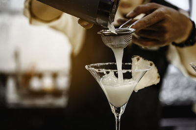 Close-up of cocktail pouring in glass at bar counter