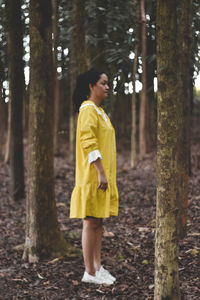 Full length of girl standing on tree trunk in forest