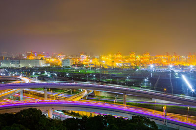 Illuminated bridge over river against sky at night