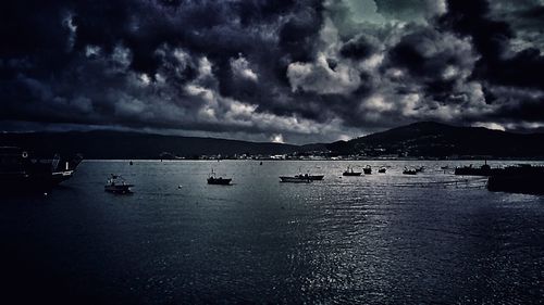 Boats in sea against cloudy sky