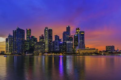 Illuminated cityscape against calm blue sea