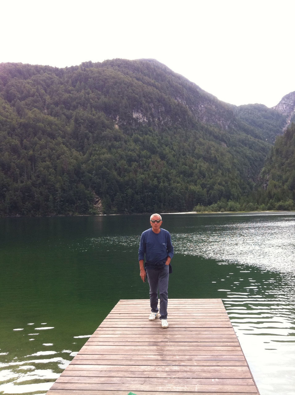 water, lake, full length, rear view, tranquil scene, tranquility, pier, lifestyles, leisure activity, scenics, tree, casual clothing, beauty in nature, nature, mountain, standing, clear sky, sky