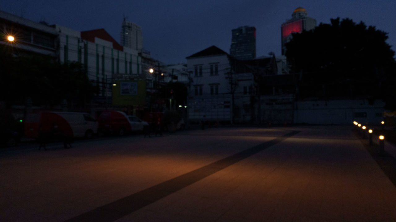 ILLUMINATED STREET BY BUILDINGS AT NIGHT