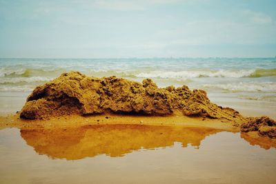 Rock formation on beach against sky