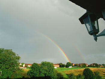 Low angle view of rainbow over trees against sky