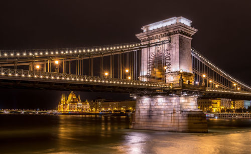 Illuminated bridge over river at night