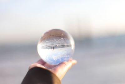 Close-up of hand holding crystal ball against water