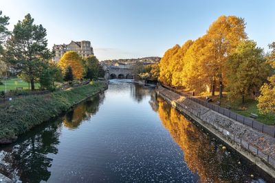 Arch bridge over river against sky during autumn