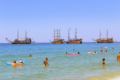 Boats in sea against clear sky