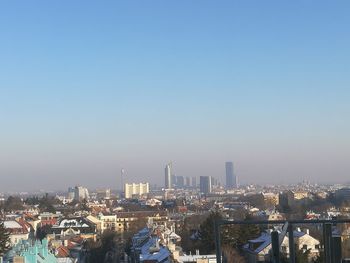 Aerial view of buildings in city against clear sky