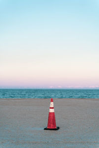 Red umbrella on beach against clear sky