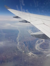 Aerial view of aircraft wing over landscape against sky