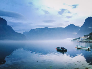 Boats in sea against cloudy sky