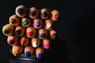 Close-up of multi colored pencils on table against black background