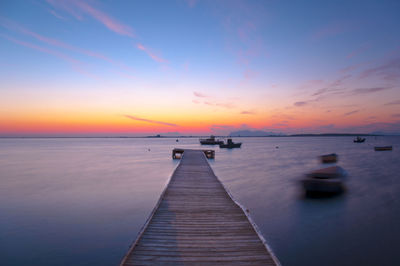 Pier over sea against sky during sunset