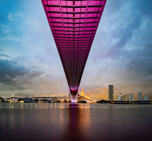 View of illuminated bridge over river against buildings