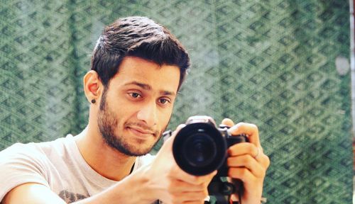 Close-up of young man photographing with camera