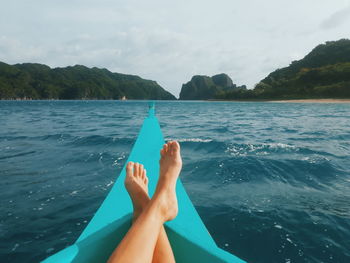 Low section of woman resting on rowboat in sea