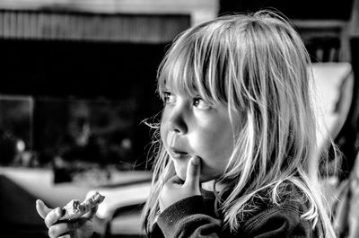 Close-up of thoughtful girl eating food at home