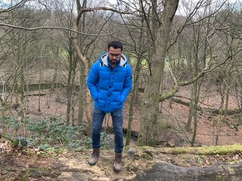 Full length of man standing amidst bare trees in forest