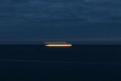 Illuminated light on beach against sky at night