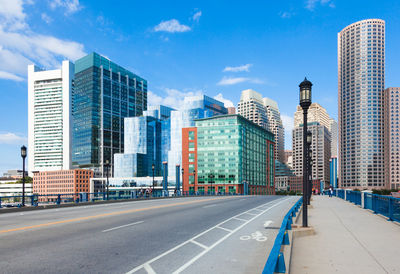 City street by modern buildings against sky