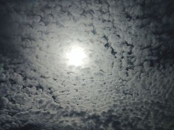 Low angle view of sun shining through clouds