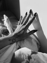 Cropped hand of woman on bed at home