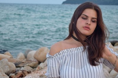 Thoughtful young woman with long hair against sea