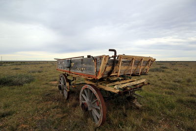 Abandoned cart on field against sky