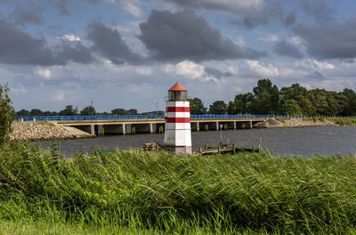 Lighthouse by river against sky