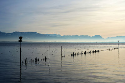 Scenic view of lake by silhouette mountains against sky during sunset